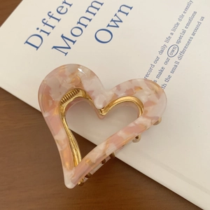 Detailed close-up of heart-shaped marble acetate hair claw with durable gold metal spring