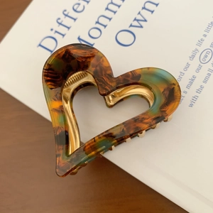 Macro detail of amber acetate heart hair claw clip with durable metal spring mechanism