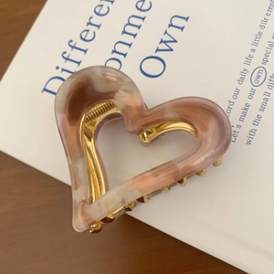 Detail shot of heart-shaped acetate claw clip with marble texture and gold metal spring