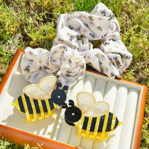 Chic acetate bee hair claw clip set with floral scrunchie on green grass background