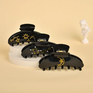 Detail view of black celestial hair claws with golden stars, moons and rhinestone accents