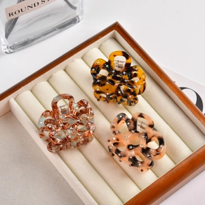 Detail of floral hollow-out acetate hair claws with sparkling rhinestones set in a tray
