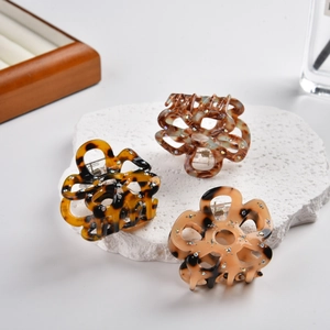 Detailed view of acetic acid flower hair claws with amber textures and rhinestones
