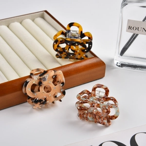 Detailed close-up of small acetate flower hair claws with leopard pattern and rhinestones