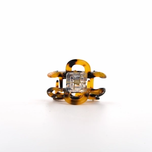 Detailed macro view of the amber textured acetate flower hair claw with small rhinestones