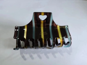 Detail of vintage striped acetate hair claw clip with heart cutout and handmade logo