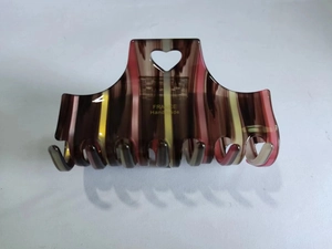 Detail view of acetate heart hair claw clip with colorful stripes and gold logo