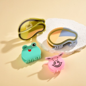 Detail view of cute acetate hair claws including pink pig and green frog animal shapes