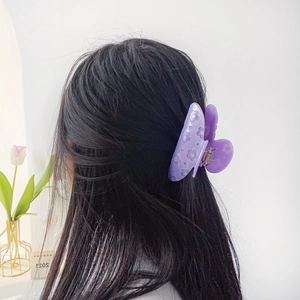 Élégante pince à cheveux fleur mate violette pour femme portée par un modèle