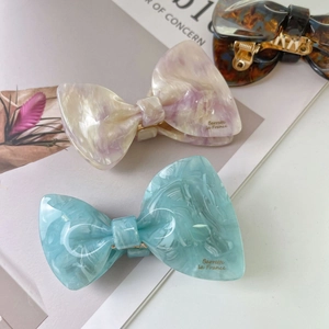 Elegant acetate bow hair claw clips with marble texture in beige and light blue tones