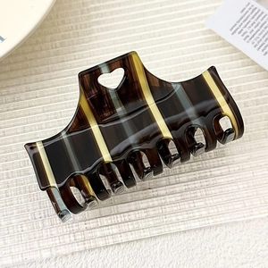 Macro shot of large acetate hair claw clip with vintage stripes and heart-shaped cutout