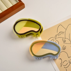 Detail of two colorful acetate hair claws with artistic color-blocking and glossy finish