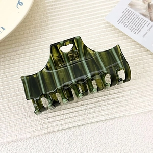 Detail of dark green striped acetate hair claw clip with unique heart cutout design