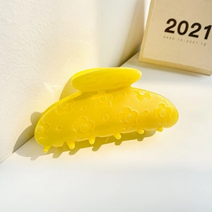 Gros plan détaillé de la pince à cheveux jaune en acétate avec motifs de fleurs