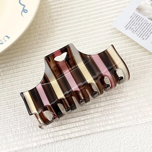 Detail showing the striped pattern and heart hollow design of the acetate hair claw clip