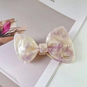 Detailed view of elegant cream and lilac acetate bow hair claw clip with marble texture