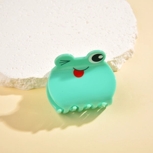 Detail of mint green frog hair claw clip on stone base with cute cartoon expression