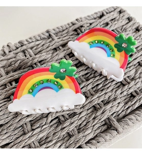 Dettaglio di mollette per capelli arcobaleno con nuvole e strass su fondo testurizzato