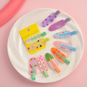 Close-up of colorful fruit theme hair clips with grape and peach patterns on a plate