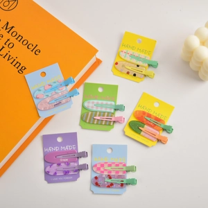 Detail of fruit-themed hair clip sets including peach and grape designs on cards