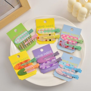 Detailed close-up of fruit-themed duckbill hair clips with peach and grape designs