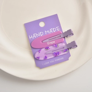 Close-up of a two-piece grape-themed hair clip set in pink and purple on card