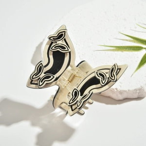 Detailansicht der Schmetterling-Haarklammer aus Acetat mit Relief auf weißem Steinpodest