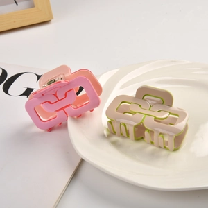 Pinces à cheveux géométriques ajourées en rose et beige sur une assiette blanche