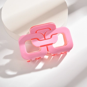 Détail d'une pince à cheveux rose géométrique ajourée avec une finition résine