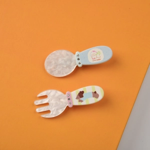 Dettaglio di fermagli creativi a forma di cucchiaio e forchetta con cuccioli e strass