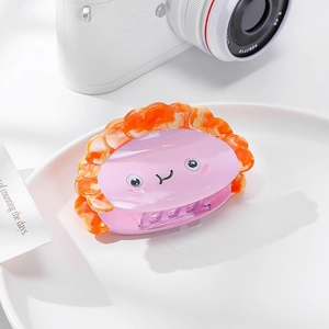 Détail macro d'une jolie pince à cheveux en acétate rose et orange sur assiette