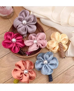 Détail de pinces à cheveux florales colorées en satin avec perle blanche au centre