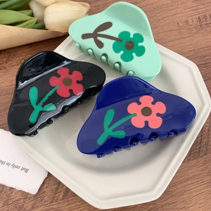 Elegante Blumen-Haarklammern aus Acetat in Grün, Schwarz und Blau auf einem Teller