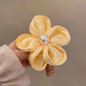 Détail d'un chouchou fleur en soie jaune avec perle blanche et élastique spirale