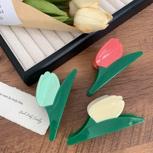 Trois pinces à cheveux tulipes en rose, vert et blanc sur un socle en bois