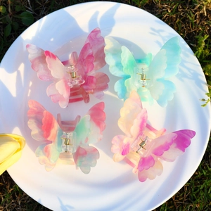 Détail de quatre pinces à cheveux papillon en acétate coloré posées sur un plateau blanc