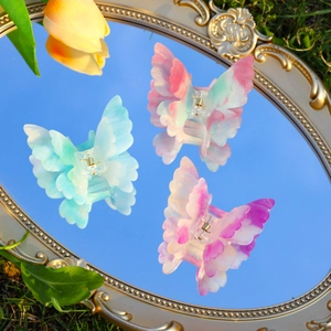 Détail de pinces à cheveux papillon en acétate pailleté se reflétant sur un miroir extérieur