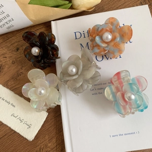 Lot de 5 pinces à cheveux fleurs en acétate avec perles sur un bureau en bois