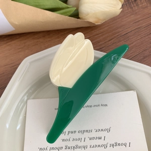 Détail macro d'une pince à cheveux tulipe en acétate dans un plat décoratif