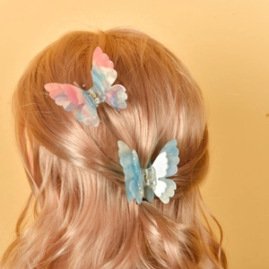 Duo de barrettes papillon en acétate coloré et bleu marbré sur cheveux de mannequin