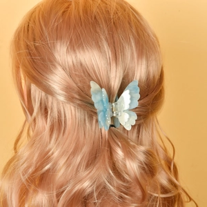 Détail d'une pince à cheveux papillon double couche avec motif marbré bleu sur les cheveux