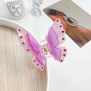 Close-up of a double-layered butterfly hair claw clip with pink crystals on a white tray