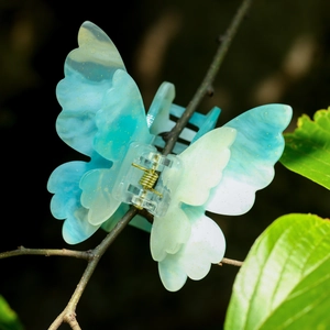 Détail d'une pince à cheveux papillon bleu clair avec paillettes dorées sur une branche