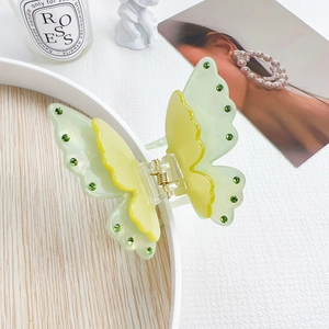 Detail view of a double-layered butterfly hair claw clip with green rhinestones and spring