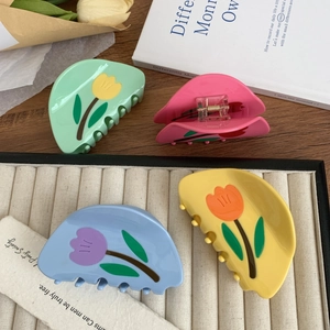 Pinces à cheveux tulipe élégantes en acétate aux couleurs macaron sur une table en bois