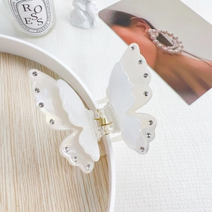 Macro detail of the metal spring mechanism on a white butterfly rhinestone hair claw