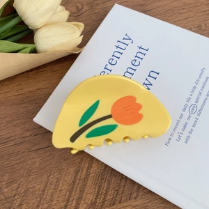 Détail de la pince à cheveux en acétate jaune avec motif tulipes et finition brillante