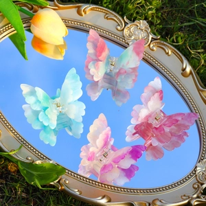 Pinces à cheveux papillon colorées en acétate posées sur un miroir reflétant le ciel bleu clair