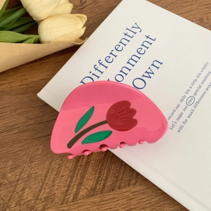 Détail d'une pince à cheveux fleurie en acétate rose avec motif tulipe sur fond lifestyle