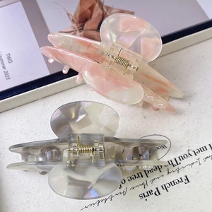 Detailed macro view of large starfish hair claws with premium marble texture and metal spring